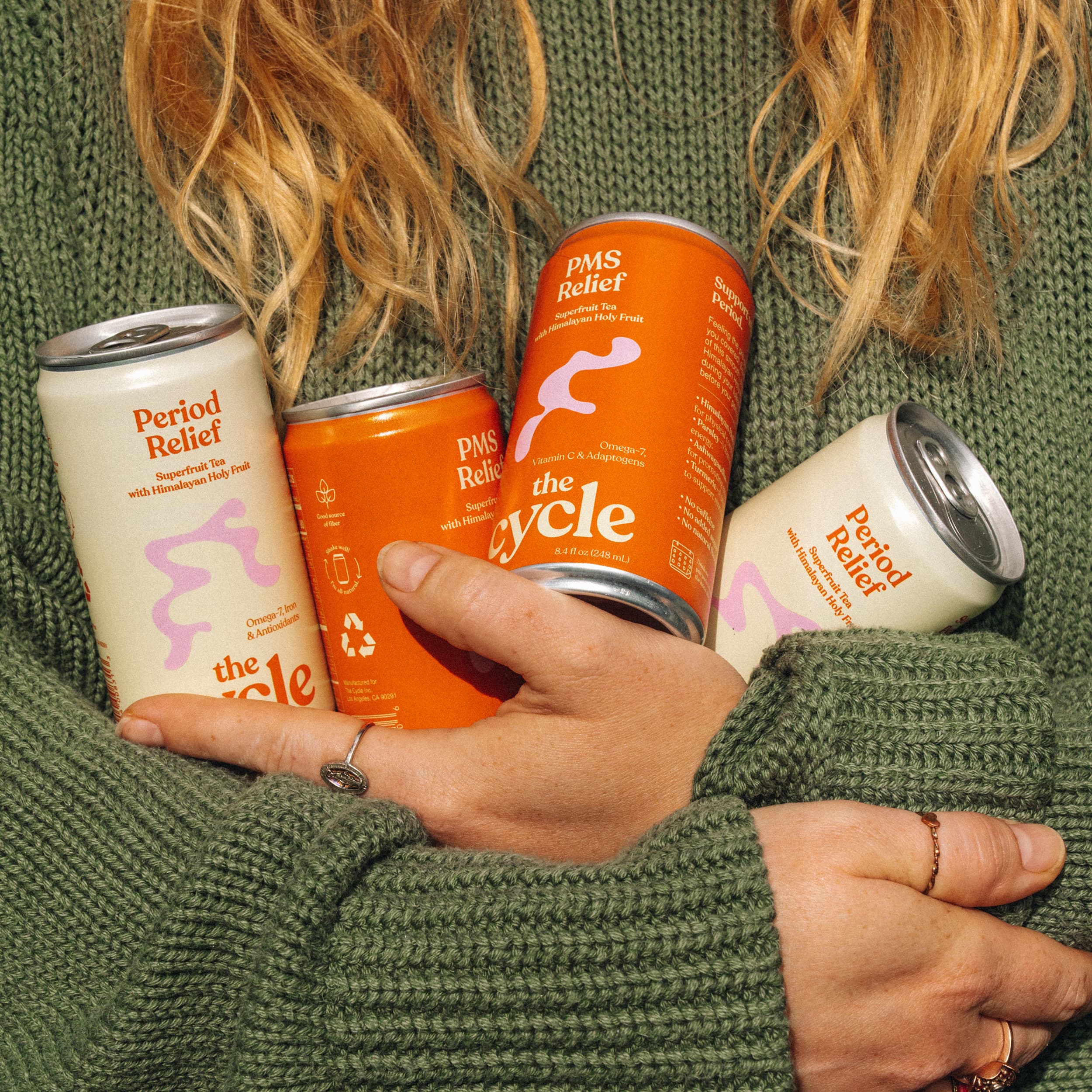 Hands holding The Cycle cans